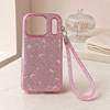 Pink glitter bow iPhone 17 Pro case and matching wrist strap in a lifestyle setting
